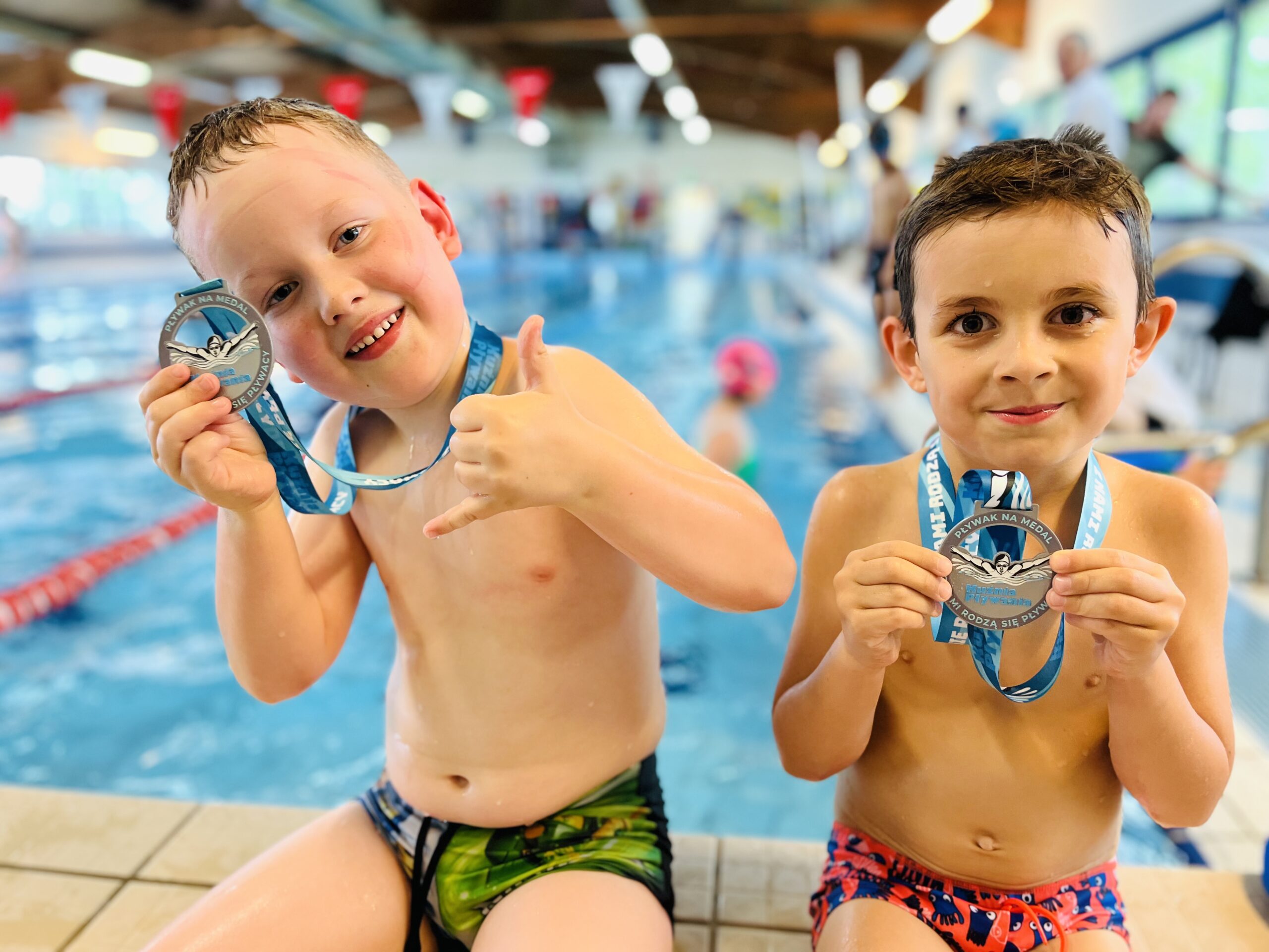 Dzieci uczące się nauki pływania, pozują z medalami