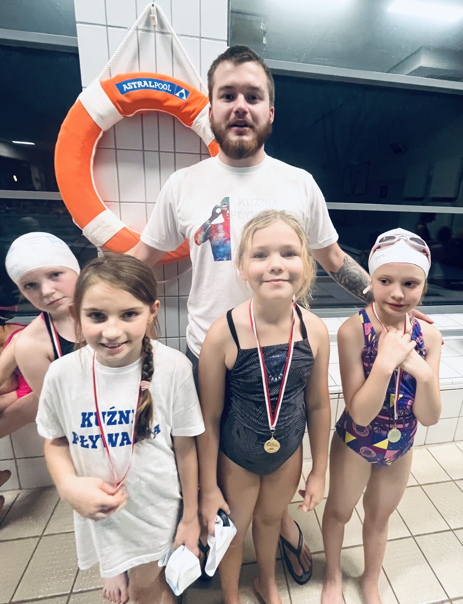 Dzieci z medalami na zawodach pływackich z trenerem